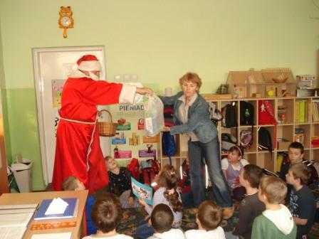 Mikołaj przekazuje prezent dla dzieci na ręce wychowawczyni świetlicy